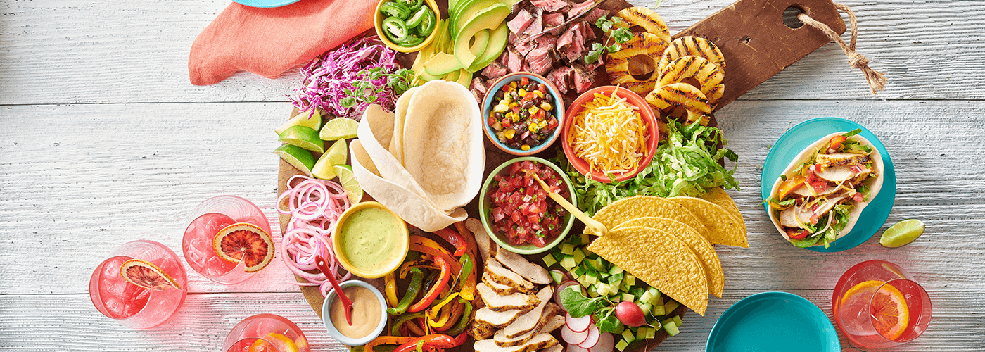 Mexican inspired charcuterie board with tacos, assorted meats, cheeses artfully arranged with fresh garnishes