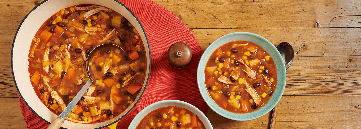 chilli soup served in a bowl accompanied by a soup pot on wooden table