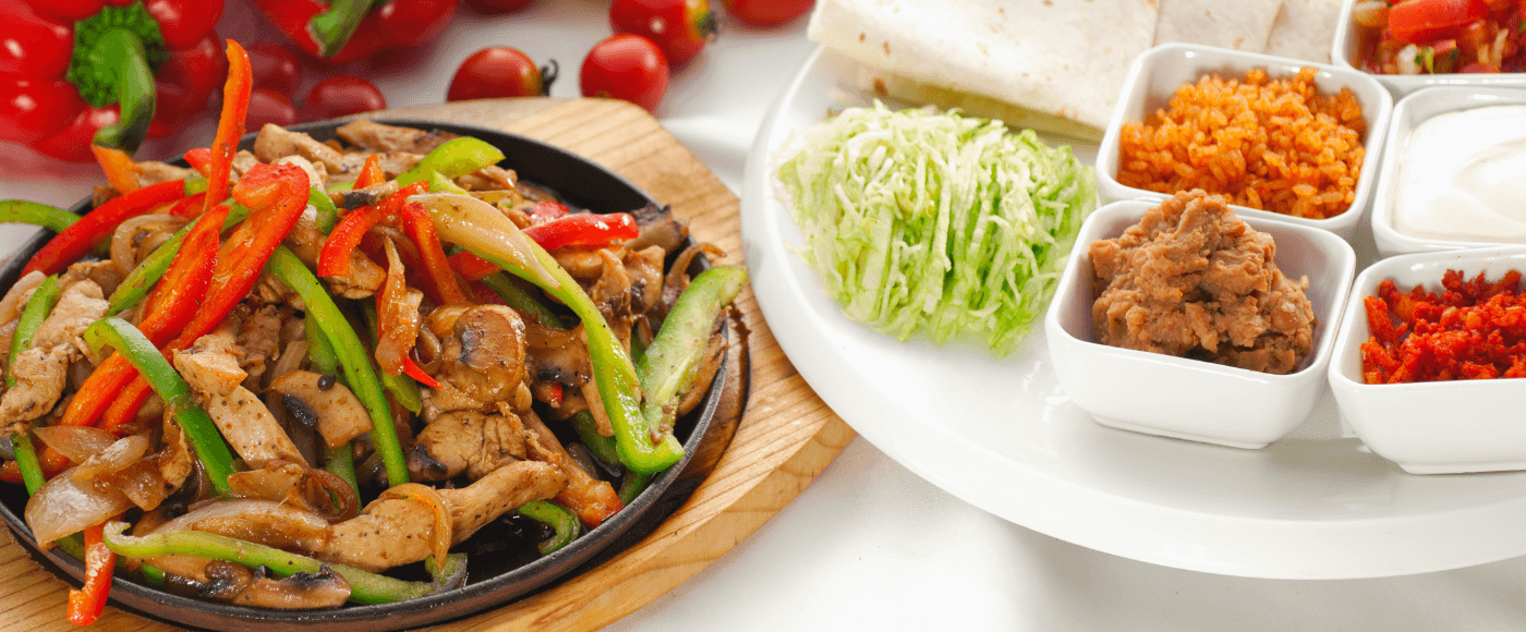 sizzling fajita on skillet surrounded by different garnishes