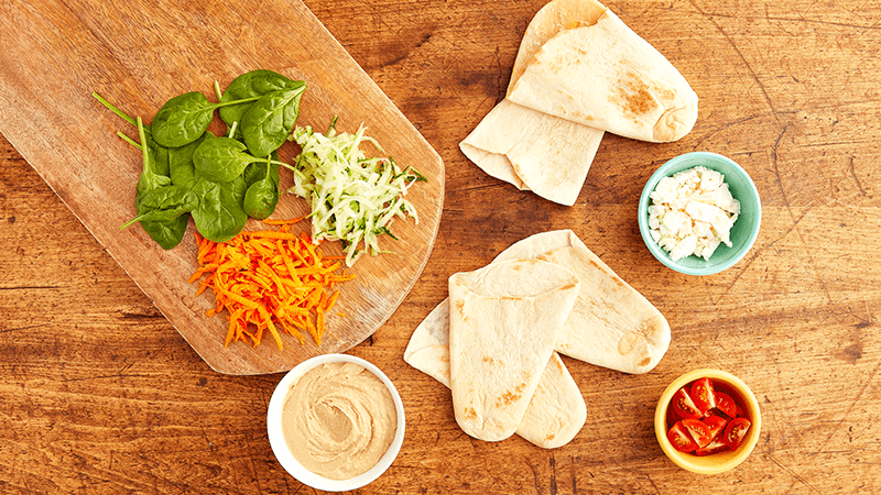 ingredients of mediterranean tortilla pockets placed on wooden board