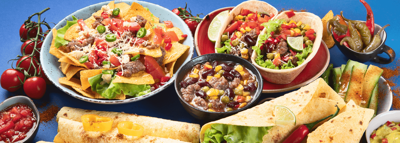delicious mexican dishes including tacos, fajita, nachos, bean soup etc. served on table