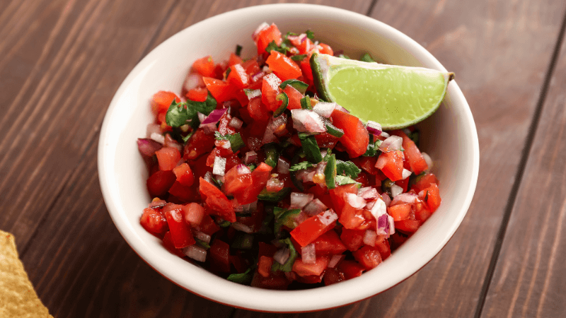 tomato salsa topped with lime wedge served in a white bowl