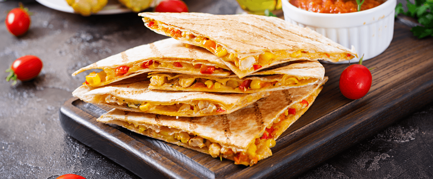 quesadillas served on a wooden plate with cherry tomatoes around