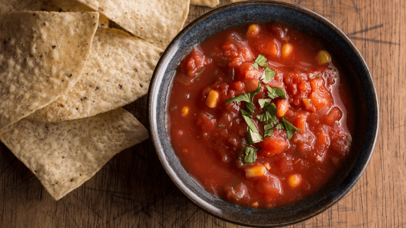roasted tomato salsa serve in black bowl with tortillas on wooden board