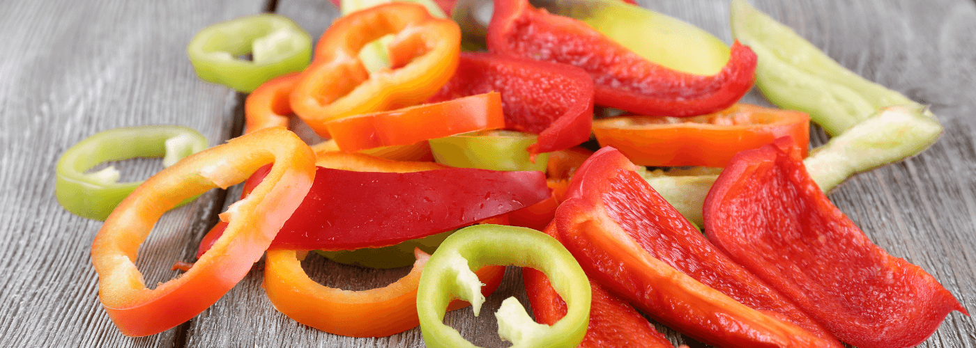 sliced red, green & yellow peppers kept on wooden board