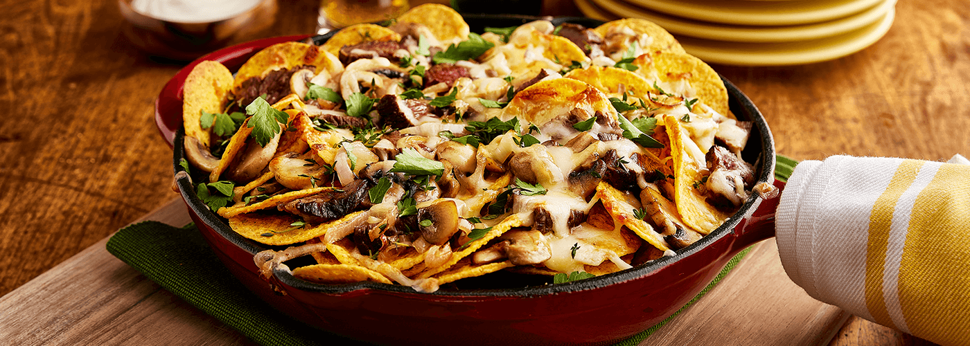 steak nachos served in frying pan placed on wooden board