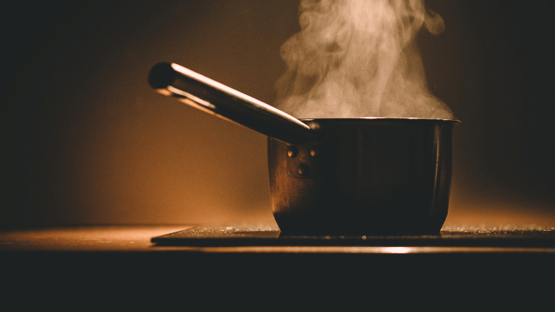 steaming pot on wooden surface with a warm orange glow in the background