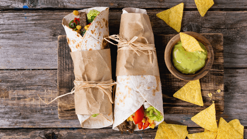 tortillas & nachos served on wooden board with guacamole dip