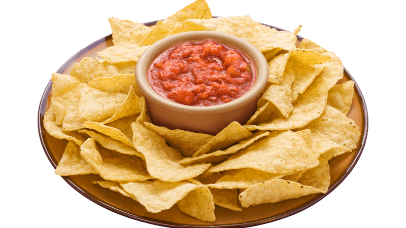 tomato salsa served in a bowl with chips on a brown plate