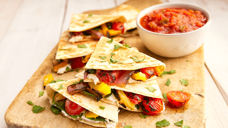 Charred Veggie Quesadillas with Goat Cheese served on wooden plate with salsa