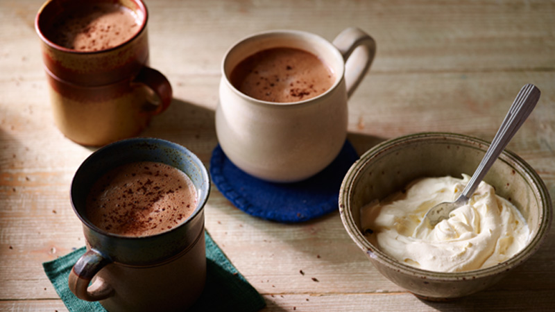 Mexican hot cocoa served in three cups with decadent whipped cream