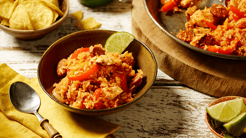 bayou sausage jambalaya garnished with lime wedges served in a brown bowl