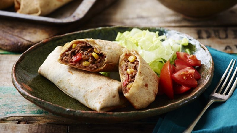 Baked Beef and Bean Chimichangas served in a plate with shredded cabbage & dice tomatoes