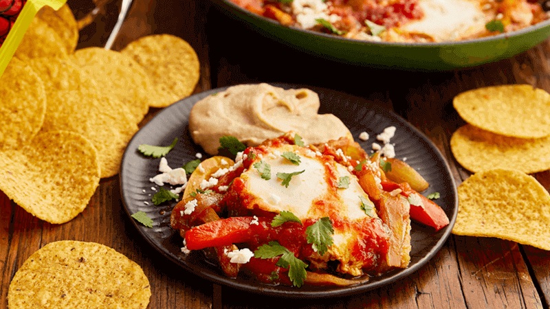 Mexican Shakshuka served in a black plate with crunchy tortilla chips